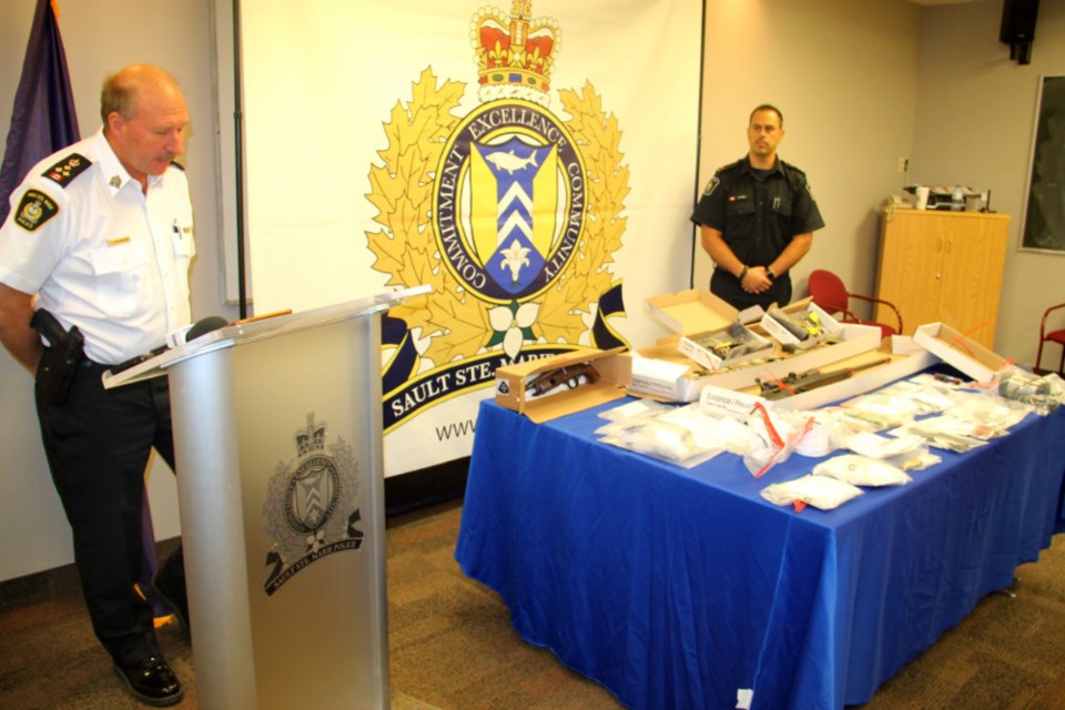 Sault Police Chief Hugh Stevenson and Cst. Sonny Spina display weapons, cash and drugs seized by Project H.E.A.T, July 31, 2018. Darren Taylor/SooToday