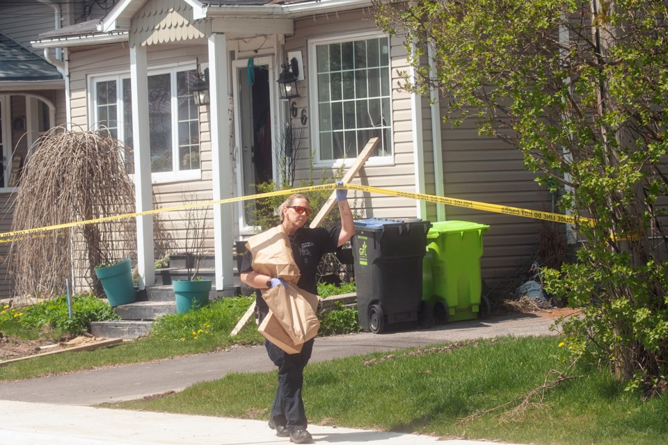 A forensics officer with the Sault Ste. Marie Police Service carries evidence bags from a home at 66 Wemyss St. on Monday. The home is the scene of a double shooting that occurred on May 11.