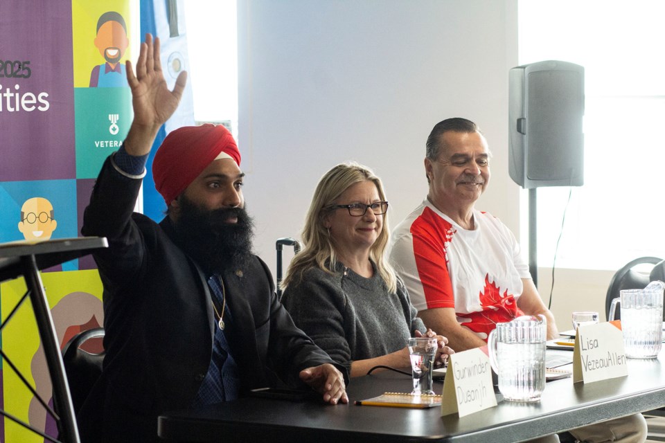 Gurwinder Dusanjh of the Liberal Party of Ontario raises his hand during an all-candidates meeting held Thursday at the Royal Canadian Legion Branch 25 while NDP candidate Lisa Vezeau-Allen and Arnold Heino of the New Blue Party look on.