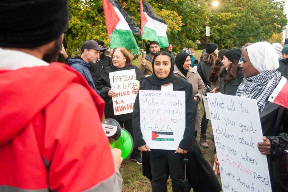 Protesters holding signs in front of city hall during the 'All Out for Gaza' protest Friday evening in the city's downtown.