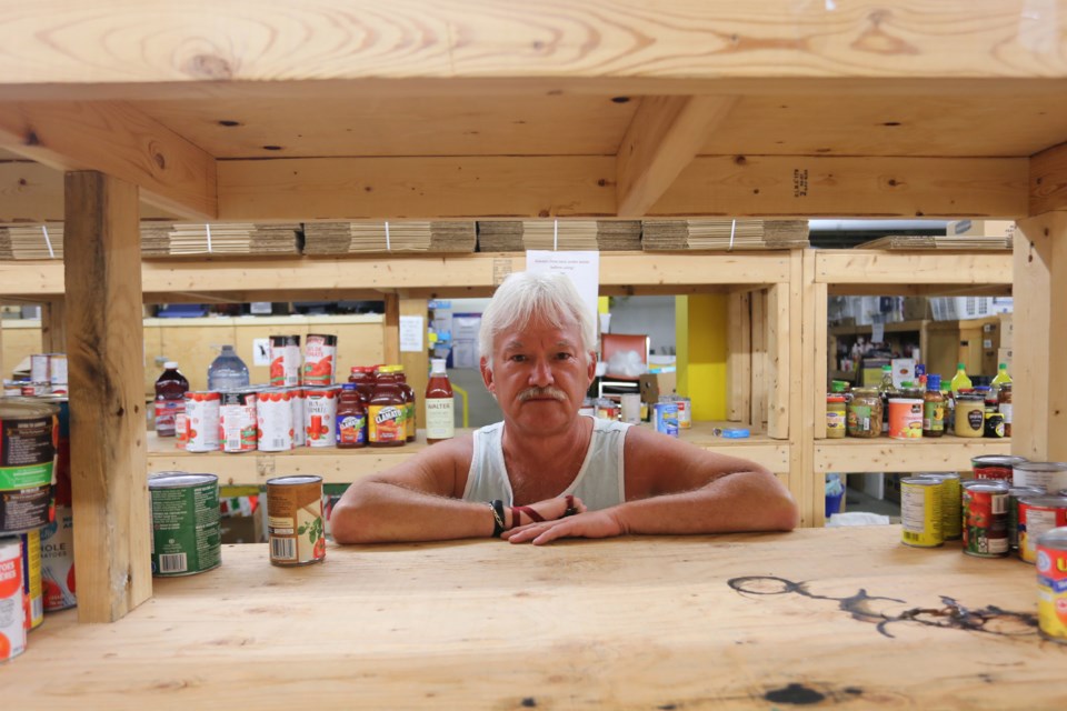 Ron Sim, general manager of the Soup Kitchen Community Centre, poses against one of the many empty shelves at the James Street facility. Earlier in the summer the shelves were filled after numerous local food drives.