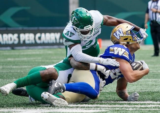 Winnipeg Blue Bombers receiver Drew Wolitarsky (82) is tackled by Saskatchewan Roughriders defenders during the first half of preseason CFL football action.