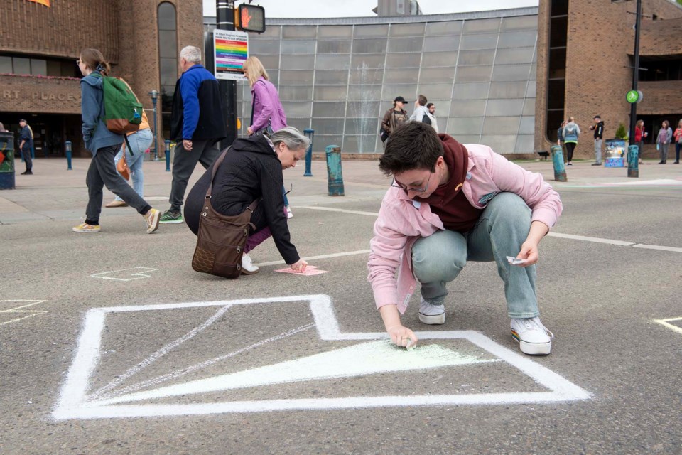 PRIDE PREP — St. Albert resident Syd J. (in pink) uses chalk to colour an image on St. Anne St. prior to the 2024 Pride crosswalk painting on May 26, 2024. The painting was cancelled due to heavy rain. City of St. Albert volunteers were set to finish the painting later that week. KEVIN MA/St. Albert Gazette