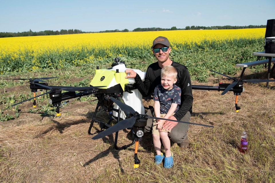 FLYING FARMER — Conor Speers and son Henry Speers examine a SkyFarm Solutions drone Speers showed to Sturgeon County farmers during the 2024 Agricultural Services Board Tour. Speers said drones such as these could soon help farmers spray fields at low cost. KEVIN MA/St. Albert Gazette