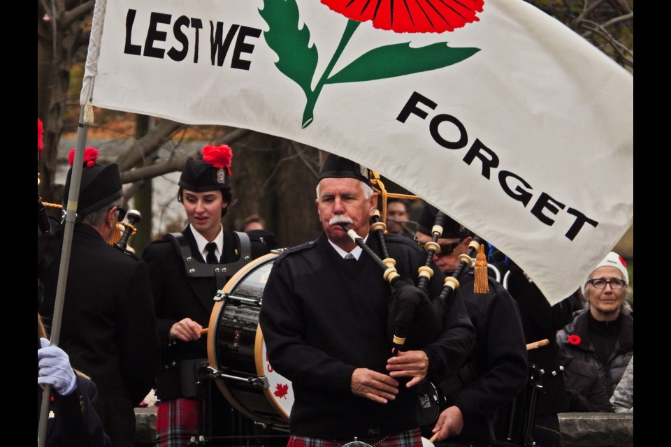 John McDonald and Cassie Klynstra of the Stratford Police Pipes and Drums play under the Lest We Forget banner during the service.         