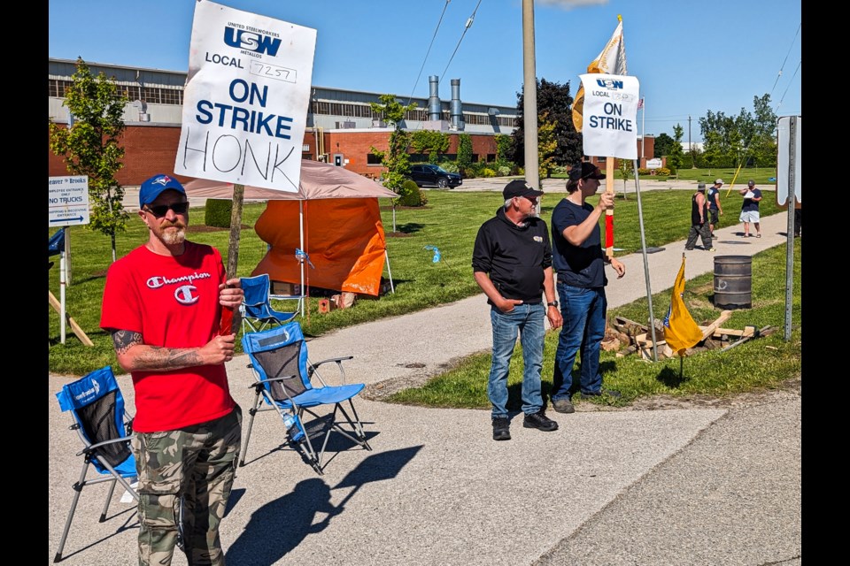 Cleaver-Brooks employees (from left) Jeff Dalby, Mike Mawhinney and Braydon Mossley respond to support from drivers while on the picket line outside the Lorne Avenue plant.