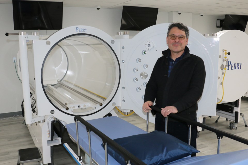 Dr. Raymond Jacques, medical director at the Sudbury Hyperbarics and Wound Care clinic, standing beside a hyperbaric chamber.