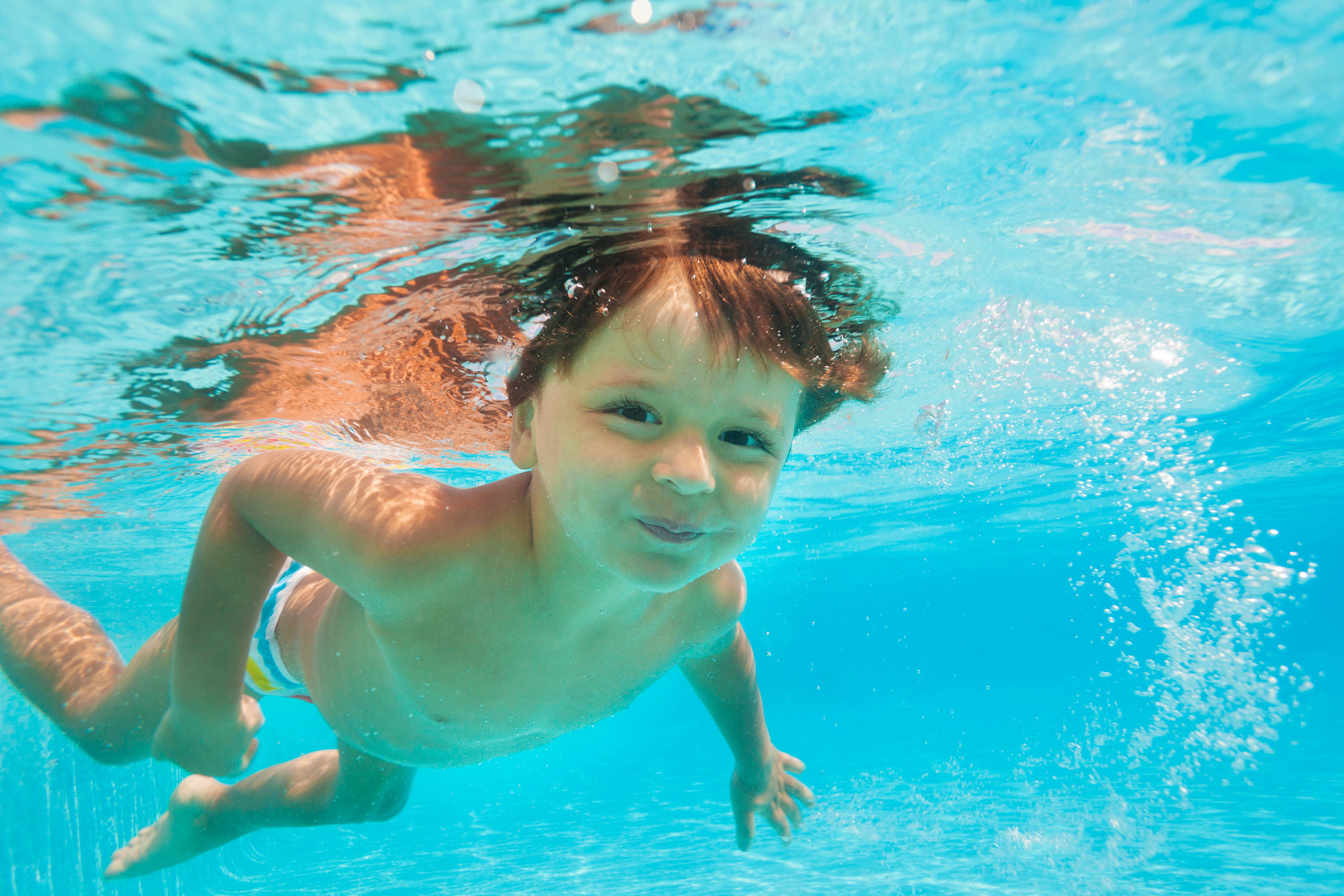 Закрыли в бассейне в воде. Мальчик плавает под водой. Мальчик плавает в бассейне. Мальчик плавает в одежде. Ребенок под водой.