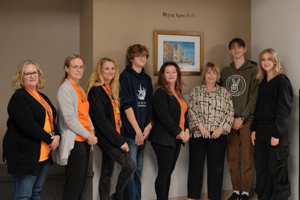 From left are Sudbury Secondary School teachers Allisyn Wood, Tara Mulcahey and Sue Bechard, student Jack Ellis, Principal Heather Downey, Donor Vicki Gilhula, and students Amon Ranger and Hannah Kaulback. Pictured with them is an original painting by artist Oryst Sawchuk