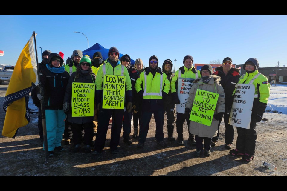 Canada Post workers hold signs and stand together during a picket line strike in Thunder Bay on Dec. 13. 