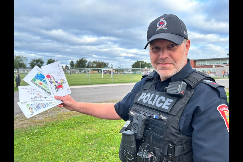 TBPS officer Tom Armstrong shows off postcards that local kids designed to remind drivers to be safe on the roads. 