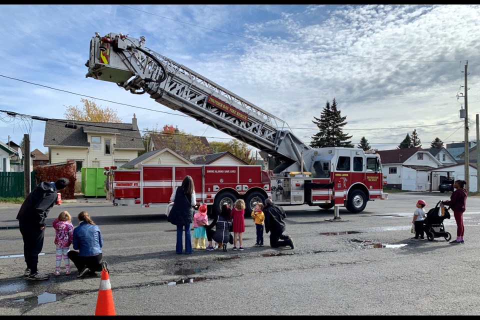 People watch as the ladder is raised on a Thunder Bay Fire Rescue truck on Saturday. 