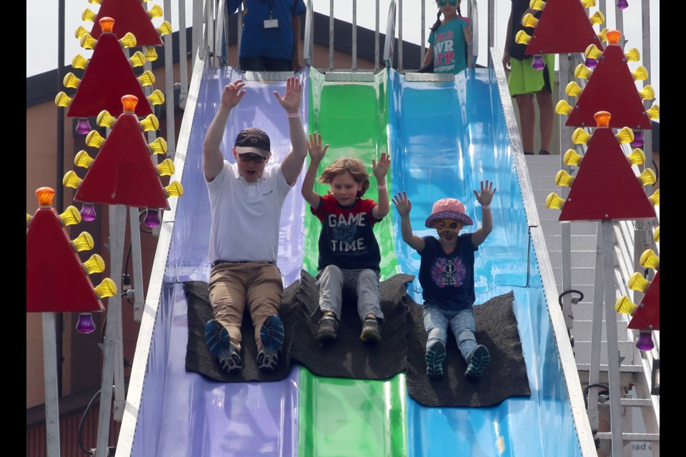 Kelvin Prosyk, eight-year-old nephew Cayman Andrews, and eight-year-old daughter, Grace, take a run down the slide at the CLE Family Fair. 