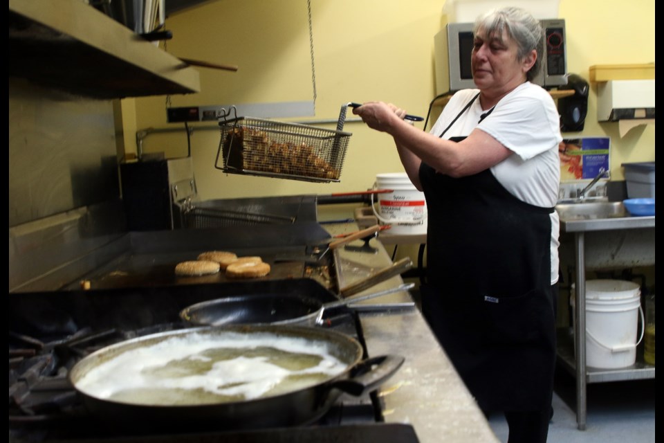 Scand House cook Flo Cormeau moves to pour breakfast potatoes from the deep fryer onto the grill. 