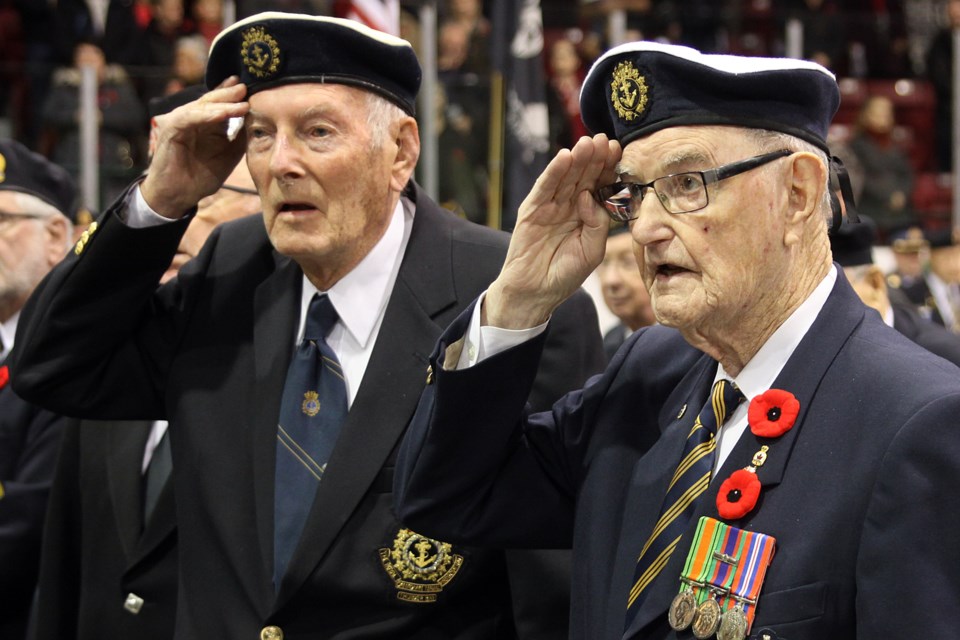 Royal Canadian Navy Second World War veterans Mo Nelson (left) and Ken MacKay salute during the Remembrance Day ceremony at the Fort William Gardens on Saturday. (Matt Vis, tbnewswatch.com)
