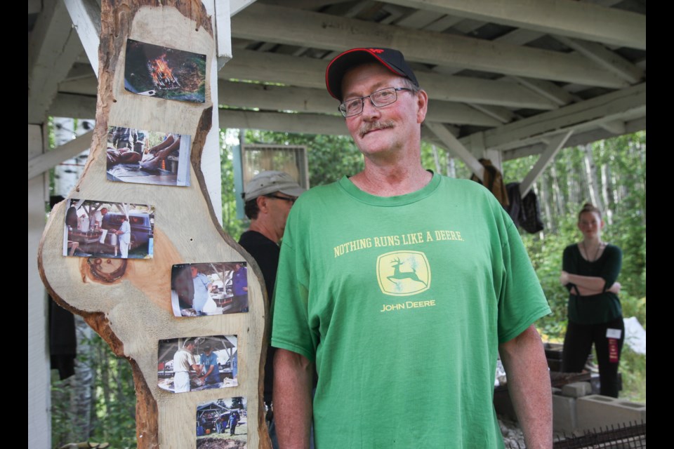 Volunteer Grant Noy stands beside the step by step process of cooking slow roasted deep pit barbecue beef.