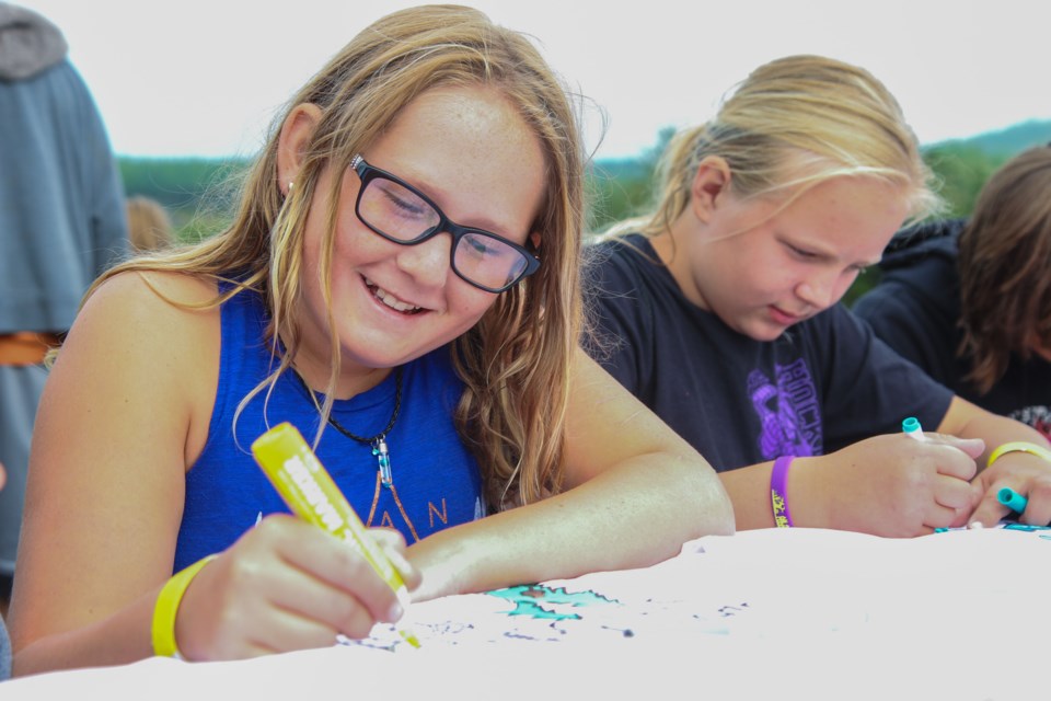 Twelve-year-old Hailey Beswetherick and 10-year-old Riley Smith decorate pillow cases for KOA Campground Halloween.