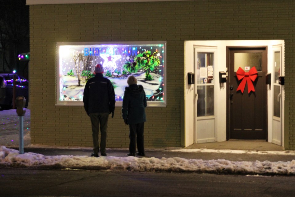 Residents inspect a holiday window painting in Westfort Saturday evening. (Photos by Ian Kaufman, tbnewswatch.com)