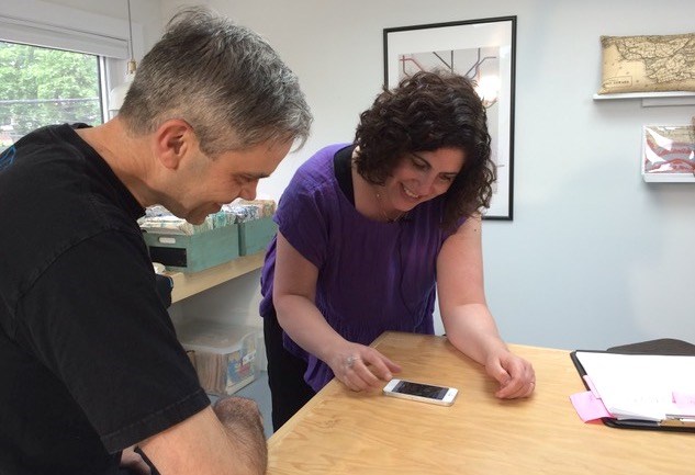 Filmmaker Kirsten Kosloski and musician Dave Ullrich of the band The Inbreds looking at old photos  of Crocks N Rolls for the documentary Five Bucks at the Door: The Story of Crocks N Rolls. (Photo is by Lieann Koivukoski). 