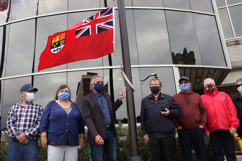 Mayor Bill Mauro (third from left) helps the family of Leo Le Feuvre raise the Red Duster on Thursday, Sept. 3, 2020 outside city hall to commemorate the service of Canadian Merchant Navy in the Second World War. (Leith Dunick, tbnewswatch.com)