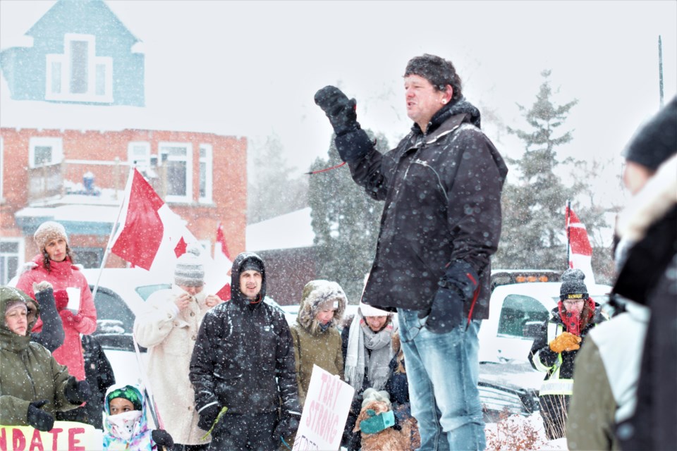 An organizer addresses a group of about 100 people who gathered at Waverley Park on Saturday, calling for an end to COVID-19 public health measures. (Photos by Ian Kaufman, TBNewswatch)