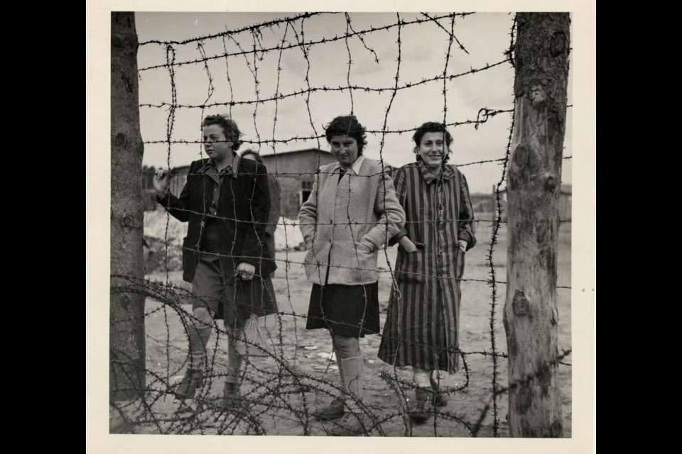 Former women prisoners stand behind a barbed wire fence at the Bergen-Belsen concentration camp after liberation in Germany in 1945 (Montreal Holocaust Museum)