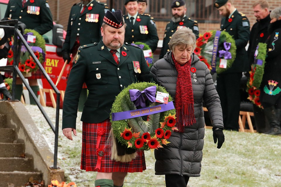 Silver Cross Mother Carol Klukie is escorted by Jim Davis to lay the first wreath on Friday, Nov. 11, 2022 at the Waverly Park cenotaph in Thunder Bay. (Leith Dunick, tbnewswatch.com)