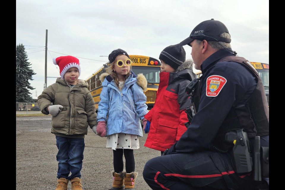 Three students at St. Bernard School speak to Thunder Bay Police Service Const. Tom Armstrong during a Tuesday media event highlighting bus safety issues. 