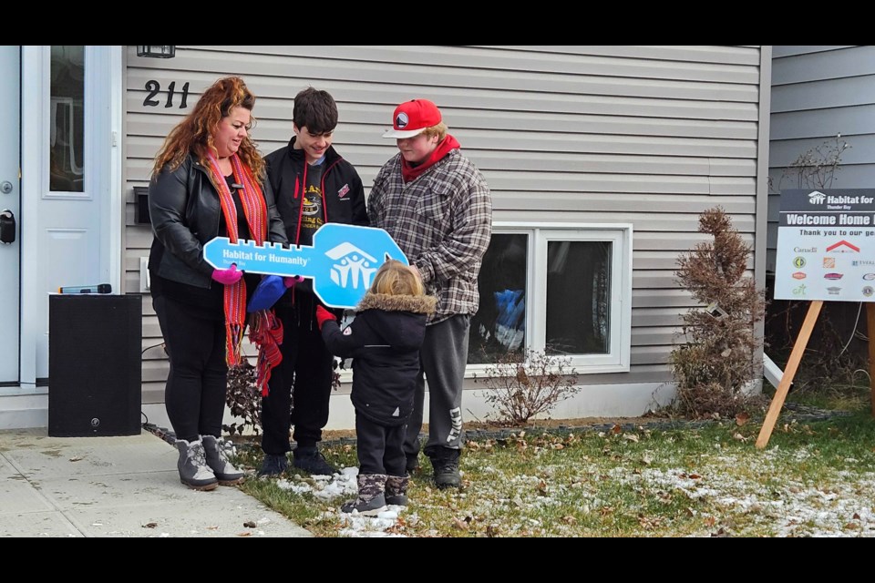 Kayla and her three boys with the "key" to their new home from Habitat Thunder Bay.