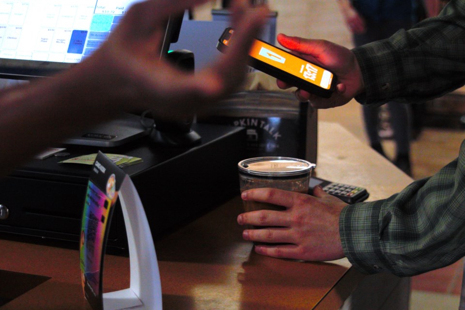 A student checks out a reusable container while paying for their drink at Lakehead's main cafeteria.