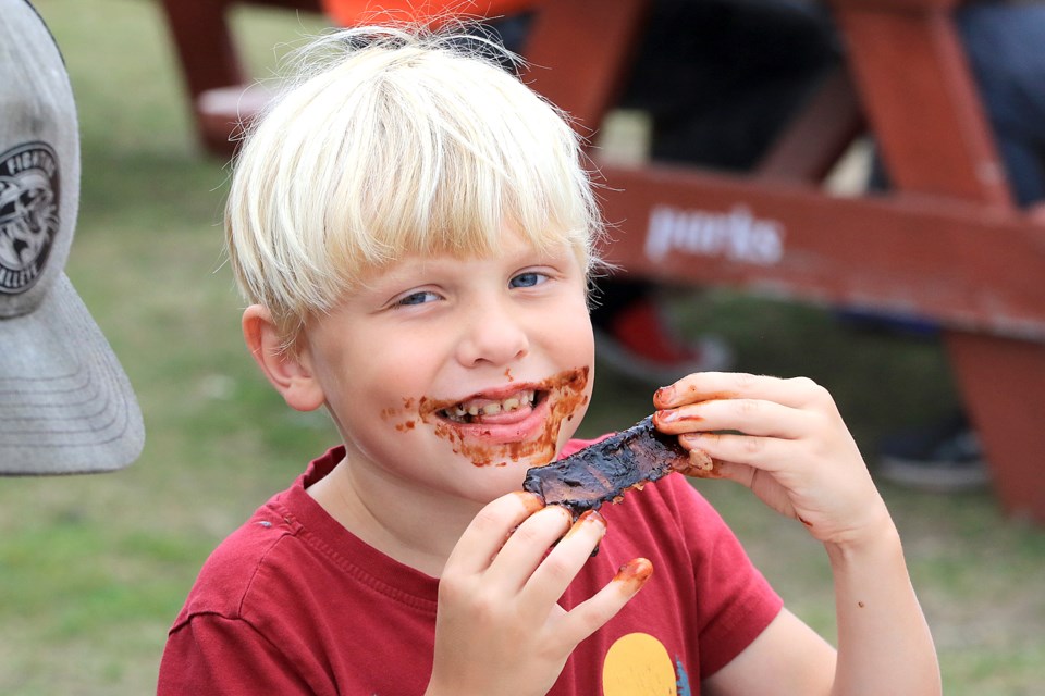 Ari Nascimben enjoys a feast of ribs on Friday, Aug. 23, 2024, Day 2 of this year's Ribfest event at Marina Park. (Leith Dunick, tbnewswatch.com)