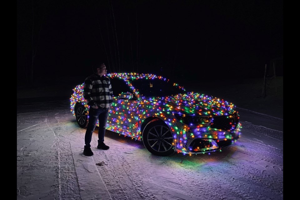 Marcus Roy poses his next to his Acura TLX, which is decorated with 2,000 holiday lights.