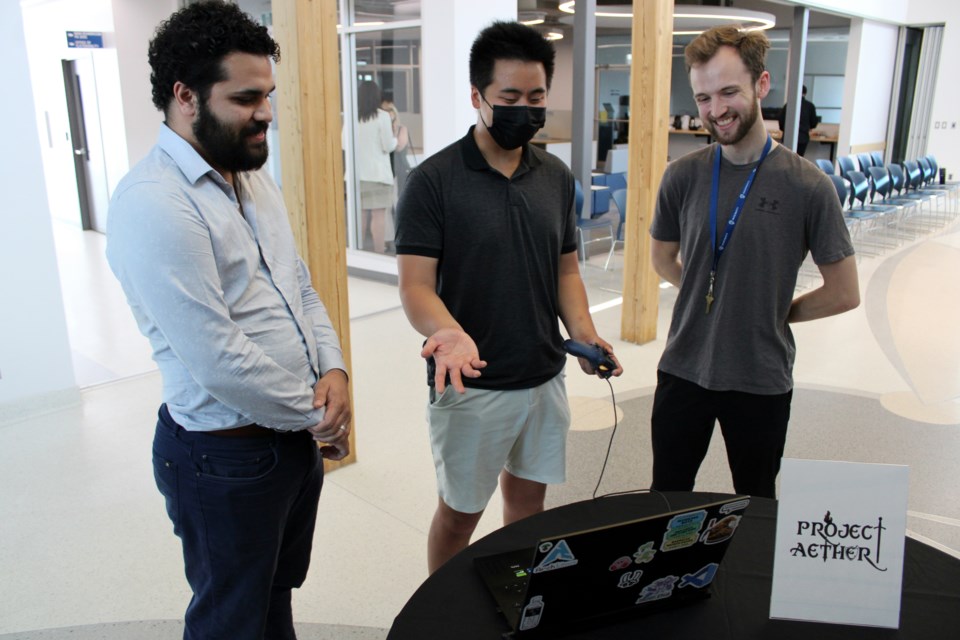 Josiah Ledua, left, James McDonagh and Tim Shaw share a laugh while showcasing their game Project Aether during the Lakehead Ingenuity's Ascend Accelerator program graduation ceremony on Friday.