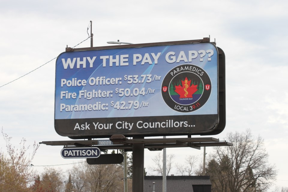 A billboard shows the difference in pay between paramedics, police and fire. 