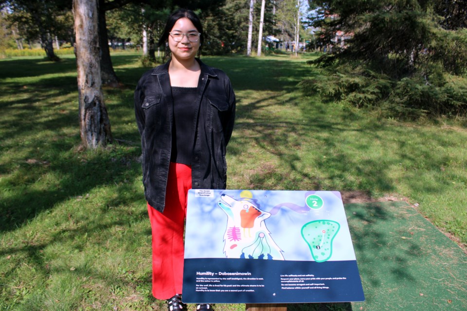 Indigenous artist Kayla Esquega stands next to one of her drawings of the Seven Grandfather Teachings that are on display at the Confederation College disc golf course.