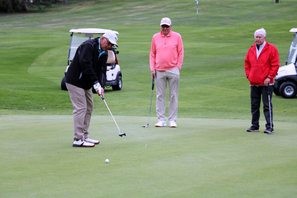 Chris Borutski makes a putt on the first green of the Strathcona Golf Course while Barry Caland and Mayor Ken Boshcoff watch during the 2024 Mayor's Mulligan. 