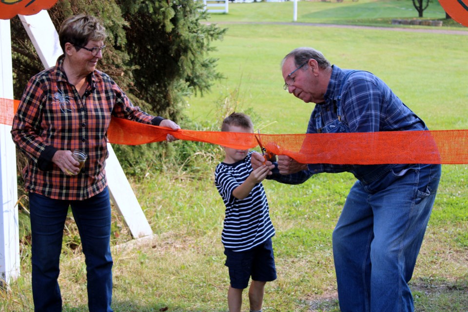 Gammondale Farms co-owner Sue Gammond watches as her husband Gerry gets help from Parker Davis in cutting the ribbon to open up the 30th and final edition of Pumpkinfest on Sept. 11.