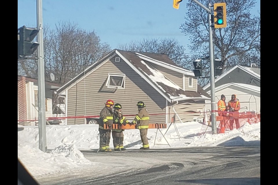 Firefighters and other workers stand outside a house that was on cribbing before it collapsed Tuesday afternoon in Fort Frances (Cynthia Smith photo)