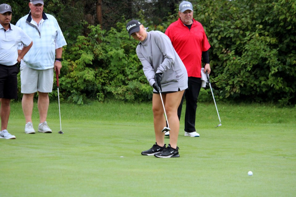 Kaitlyn Barr makes a putt while Sebastian Chambers, Jim Barr and John Heino watch on during the Raising the Barr golf tournament on Aug. 16. The tournament is held in honour of Kaitlyn's brother Dustin. 