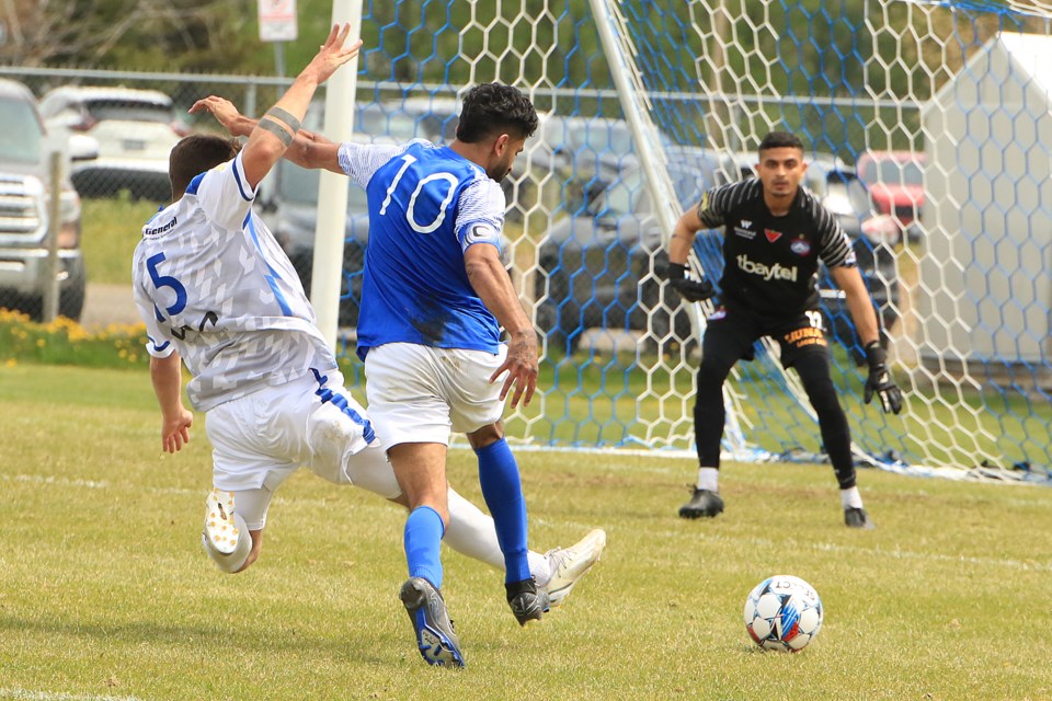 Thunder Bay's Devon Hoier (left) makes a sliding tackle to prevent a shot on goalkeeper Armaan Thawer by Winnipeg's Krish Sugumaran on Sunday, May 26, 2024 (Leith Dunick, tbnewswatch.com)