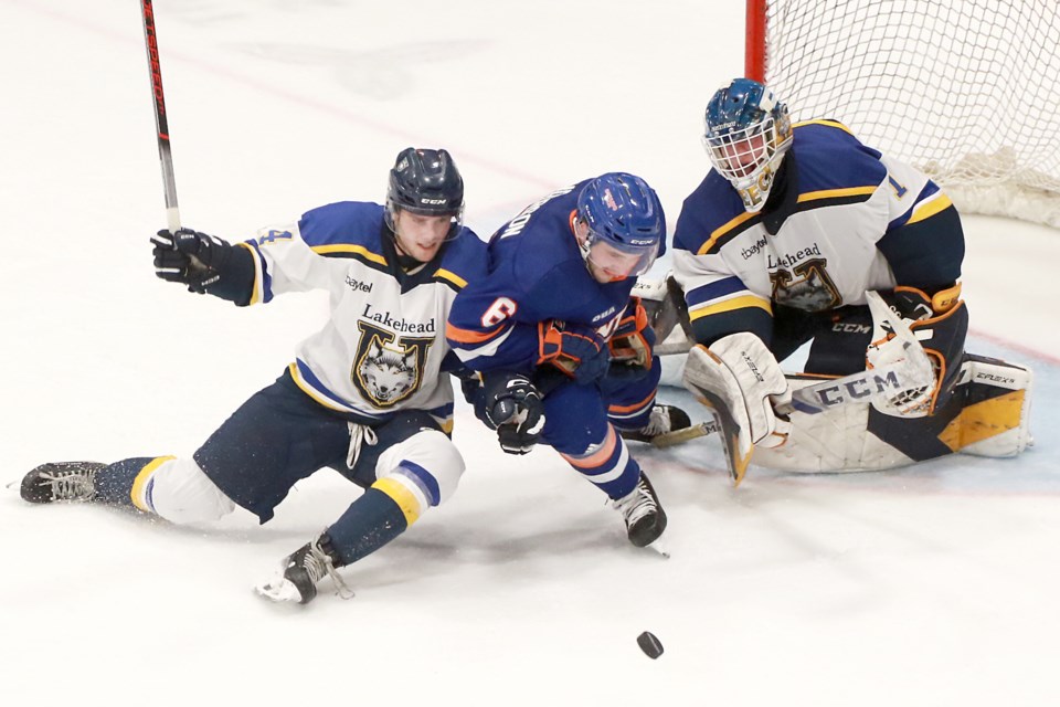 Lakehead defenceman Jayden Wojchiechowski (left) and UOIT's Baxter Anderson tangle for the puck in front of LU goaltender Christian Cicigoi on Saturday, Oct. 21, 2023 at Fort William Gardens. (Leith Dunick, tbnewswatch.com)