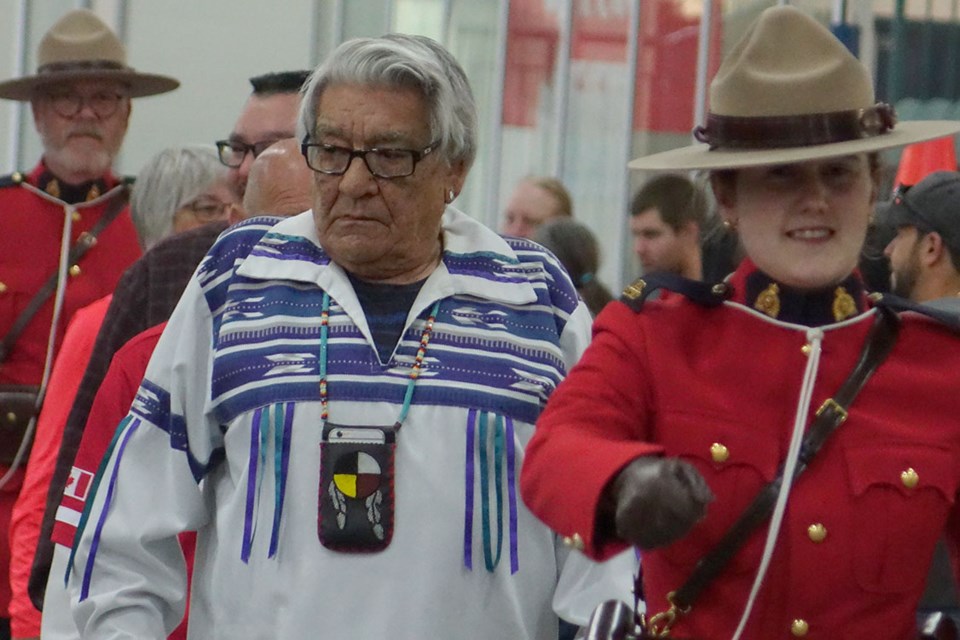 RCMP officers in red serge accompanied elder Jack Robinson and other dignitaries on and off the stage during events marking Canada Day in Thompson July 1.