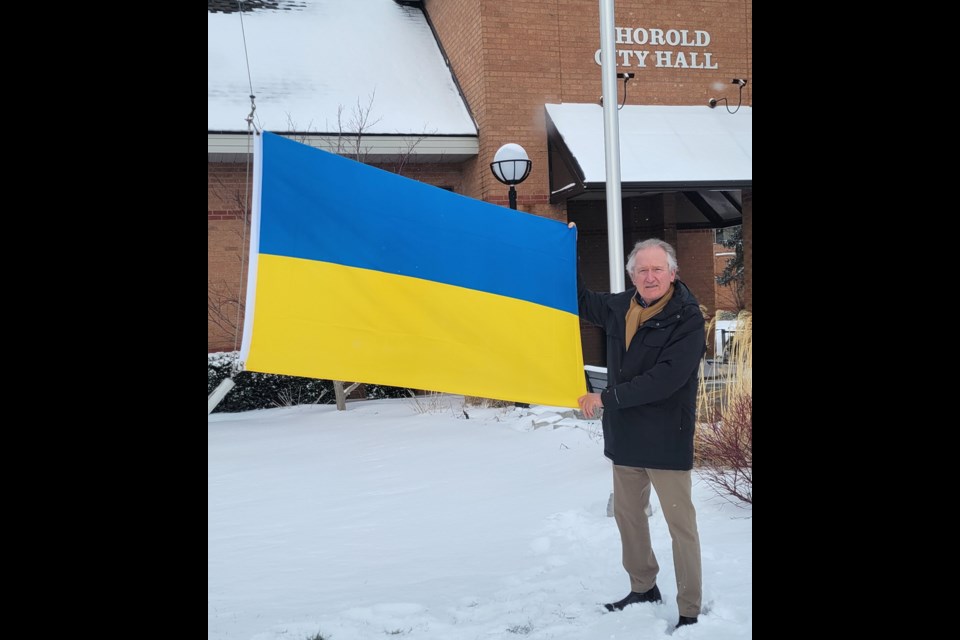 Thorold Mayor Terry Ugulini holds a Ukrainian flag that was raised at City Hall in support of the Ukrainian people facing a Russian invasion.