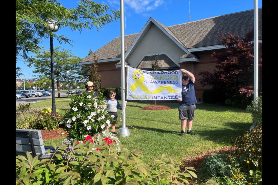 Holding up the flag are three childhood cancer survivors: Trenton, Reed, and Griffin. 