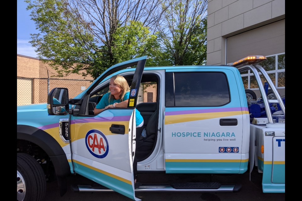 Hospice Niagara marketing Director Alicia Merry tries out the seat of the newly decorated CAA Niagara tow truck. Photo: Ludvig Drevfjall/Thorold Today