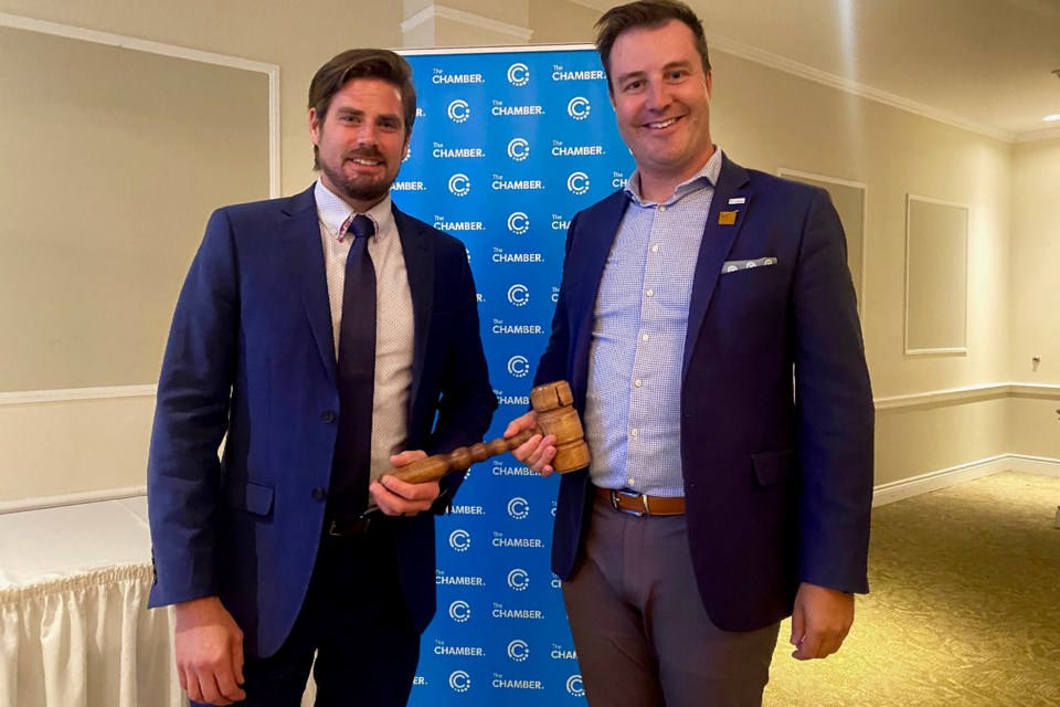 Timmins Chamber president Tom Faught, left, receives the gavel from outgoing president Kraymr Grenke.