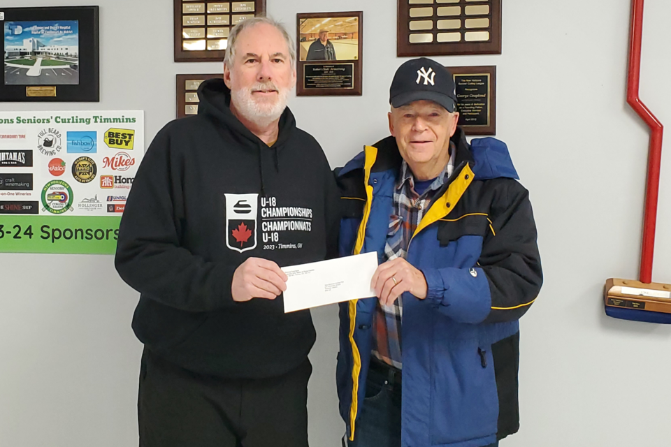 New Horizons Senior Curling League president Greg Wilson makes a donation to the Timmins Food Bank's Jim Young .