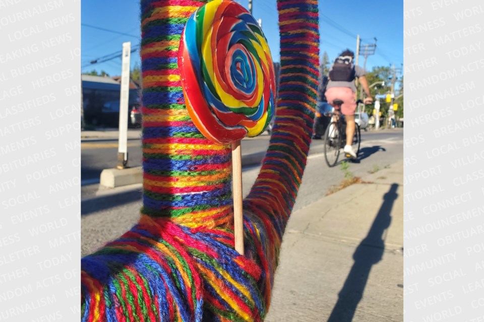 A cyclist passes by a yarn-bombed bike post, currently one of four downtown installations by street artist Martin Reis. 