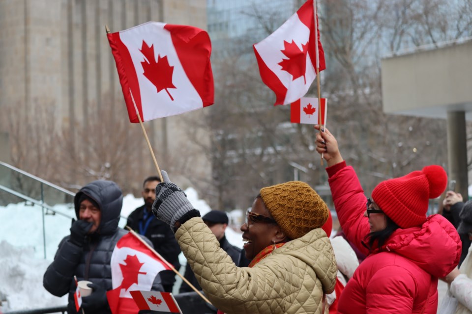 Locals proudly wave their Canadian flags at downtown event recognizing 60 years of the maple leaf on Saturday.