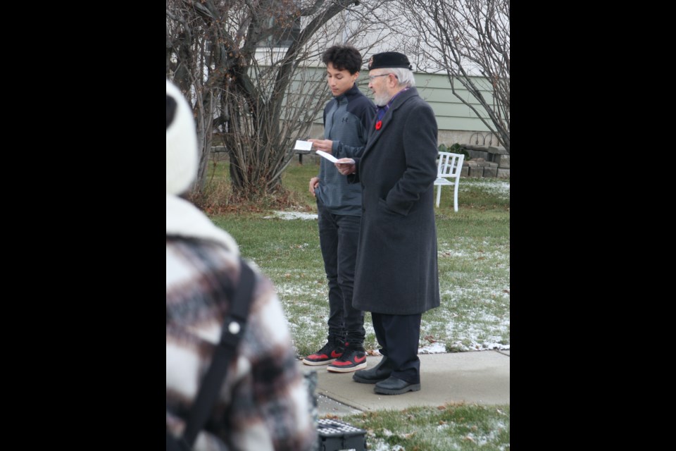 Jason Laboucane reads "In Flanders Fields" while standing beside Isaac Brower-Berkhoven, who led the Remembrance Day ceremony. The event began at the Clyde Complex, but because the weather was fairly decent that day, the attendees walked over to the Clyde cenotaph to conclude the ceremony.